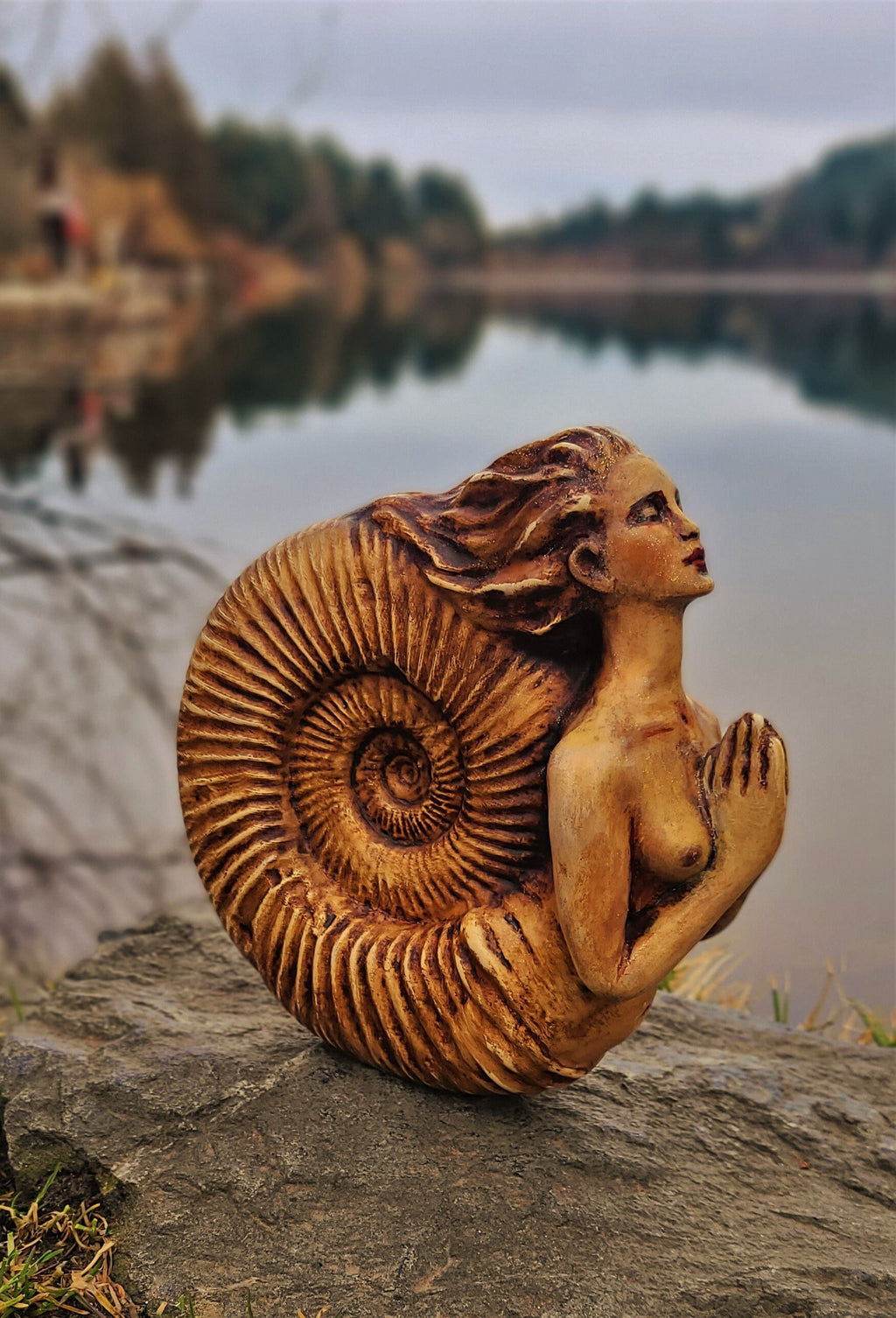 Side view of Ammonite Woman sculpture showing spiral fossil form and organic texture detail