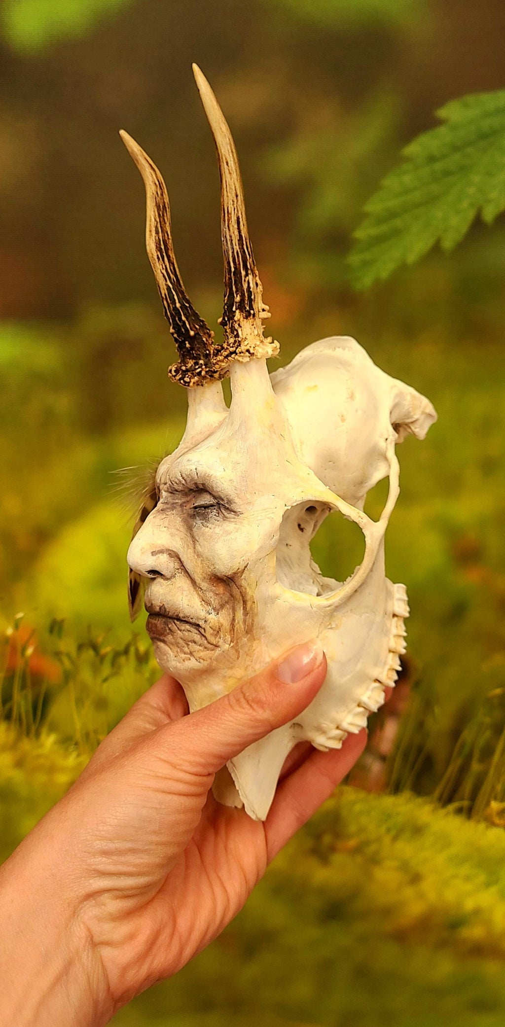 Side view of Honouring Death spirit skull sculpture showing human face emerging from skull form
