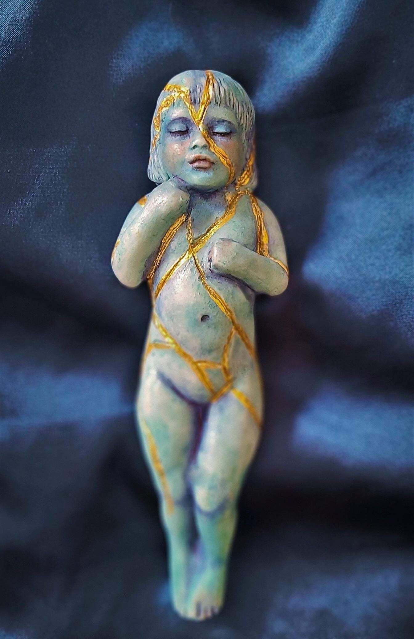 Close up of gold kintsugi repair detail on Kintsugi Child sculpture representing healing and renewal